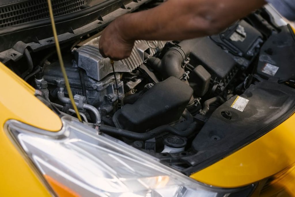 un mecanic inspecteaza motorul unei masini
